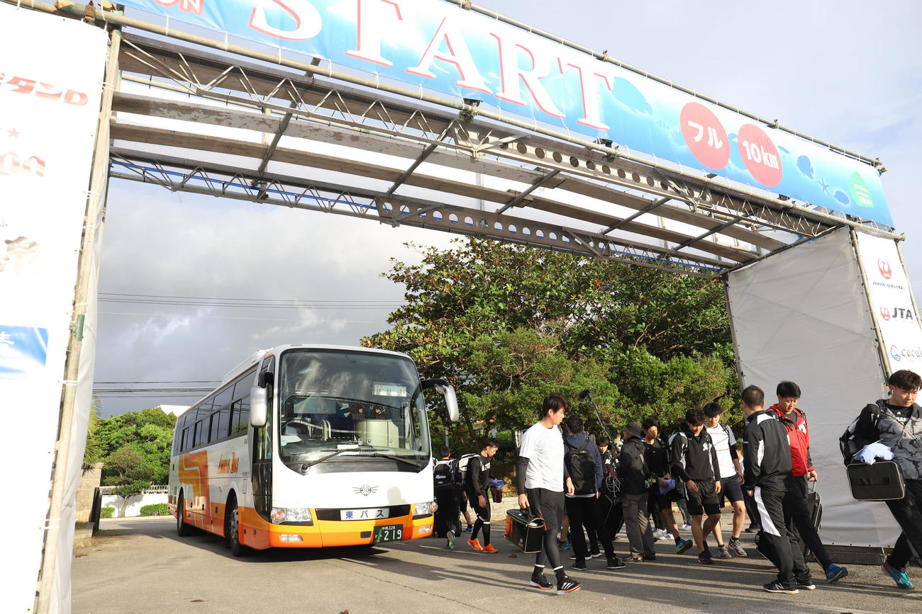 バスが前日行われたマラソンのスタートゲートにぶつかりくぐれず停車した場所から歩いて球場に向かうロッテの選手たち（撮影・垰建太）