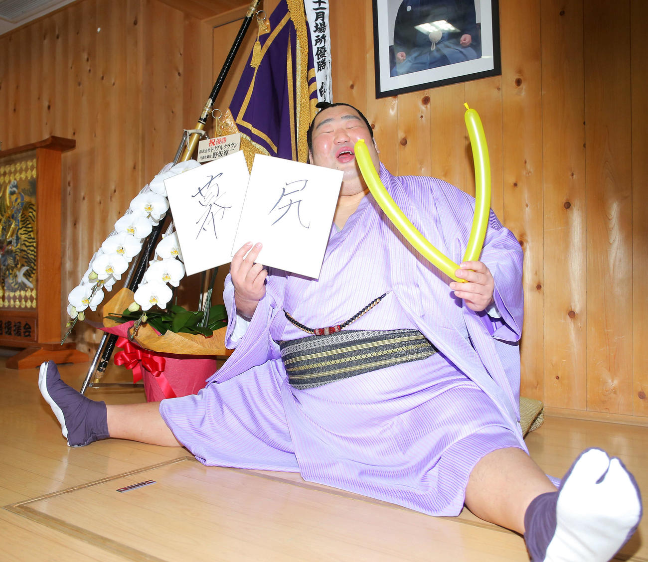 幕内優勝を飾り、一夜明け会見で「幕尻」としたためた色紙と「V」のバルーンを手におどけた表情を見せる徳勝龍（撮影・河田真司）