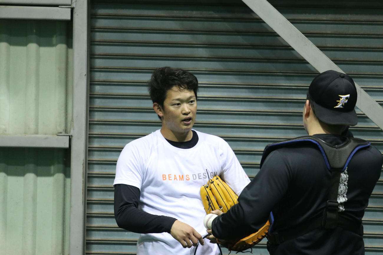 投球練習を終え、ブルペン捕手（右）と話す日本ハム鈴木健（撮影・山崎純一）