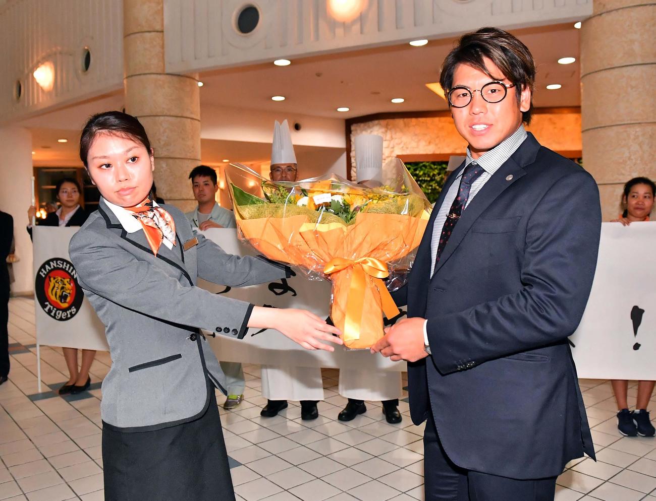 宿舎に到着し、女性スタッフから歓迎の花束を受け取る阪神梅野（撮影・上田博志）