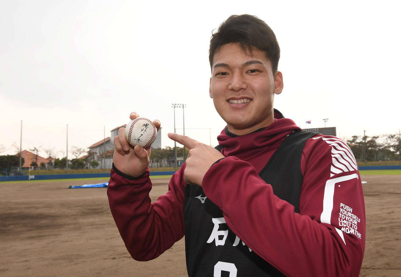 「場外1号」と記したボールにサインし、ポーズを決める中日石川昂弥（撮影・森本幸一）