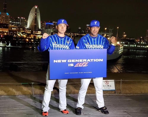 DeNA新主将に就任した佐野はラミレス監督とともに、今季のチームスローガンを掲げて横浜の夜景の前でガッツポーズ(撮影・鈴木正章)