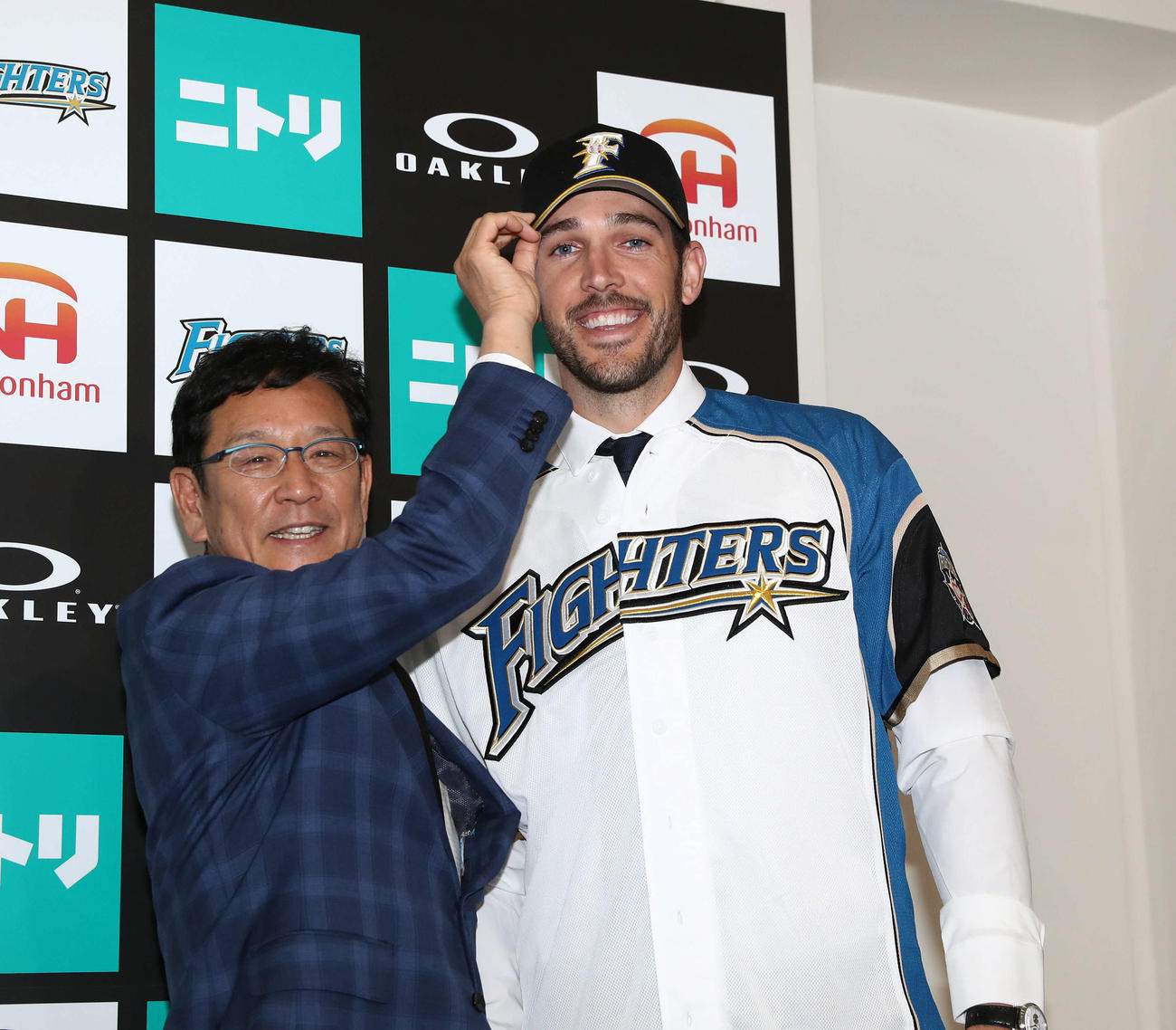 新加入のバーヘイゲン（右）に帽子をかぶせる日本ハム栗山監督（撮影・黒川智章）