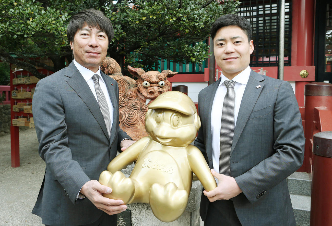 那覇市内の波之上宮で必勝祈願後、ゴールドに施したつば九郎を手に記念撮影する高津監督（左）と中村選手会長（撮影・狩俣裕三）