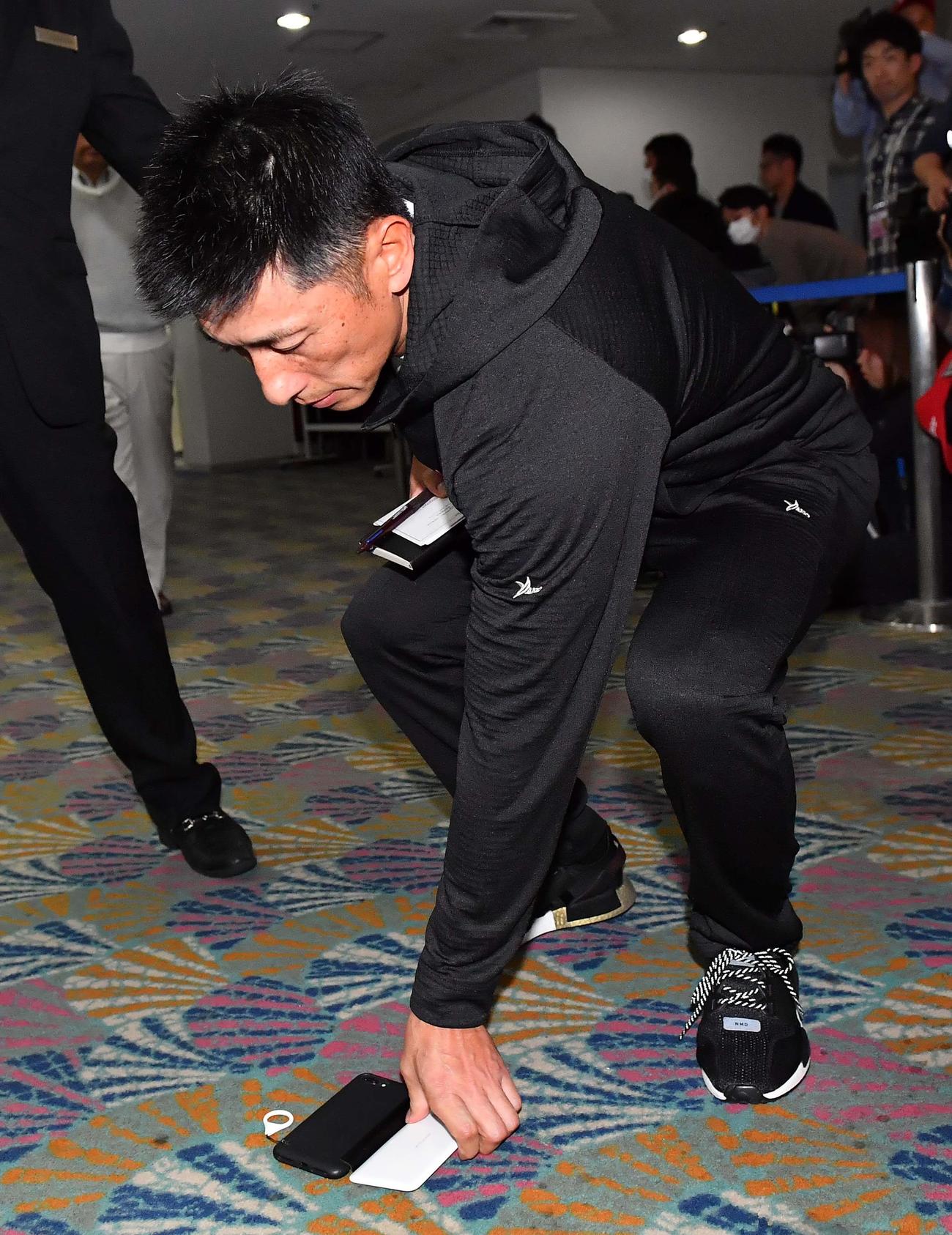 落としてしまったスマホを拾う矢野燿大監督（撮影・上田博志）