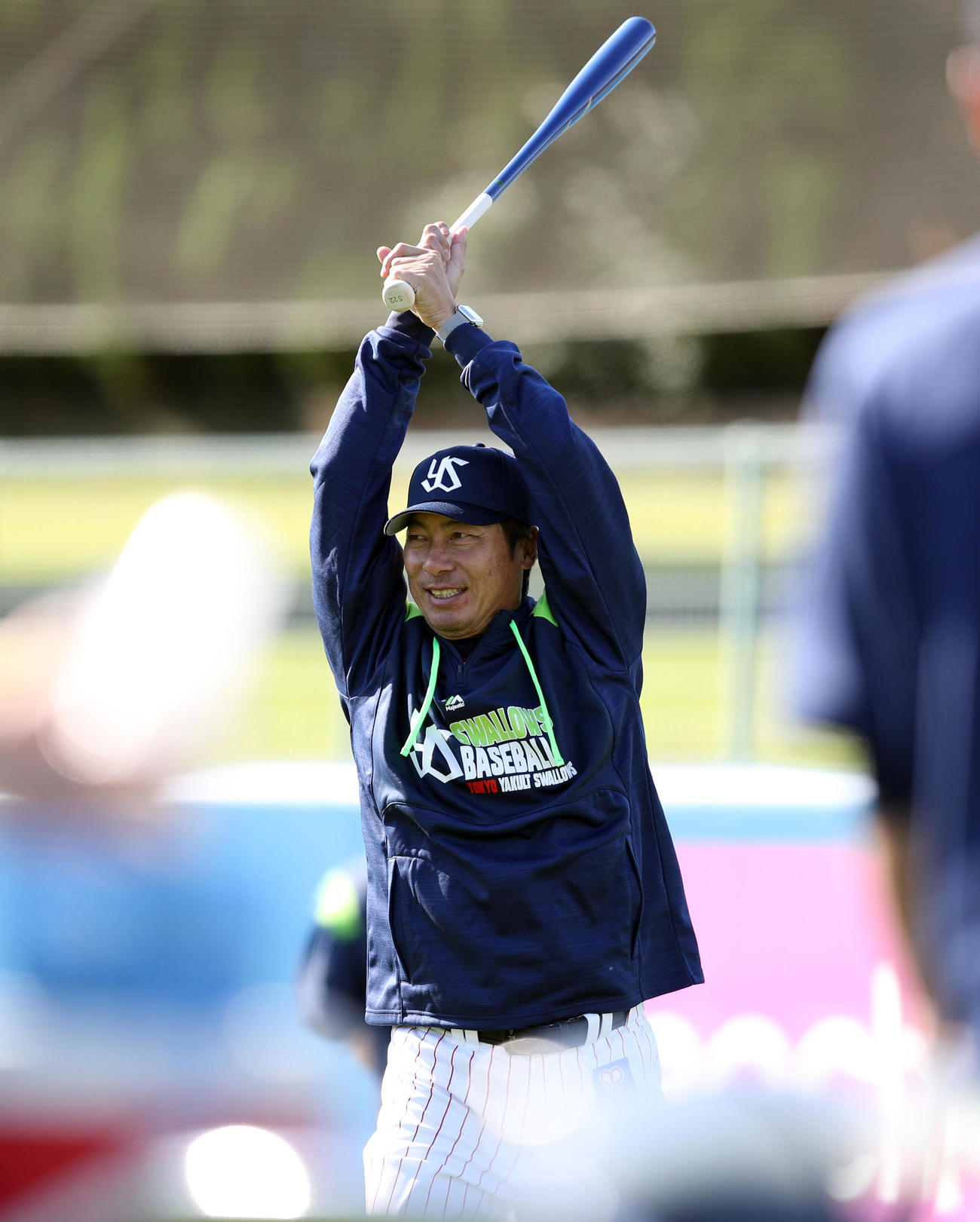 練習中、バットを振り上げ、笑顔を見せる高津監督（撮影・狩俣裕三）