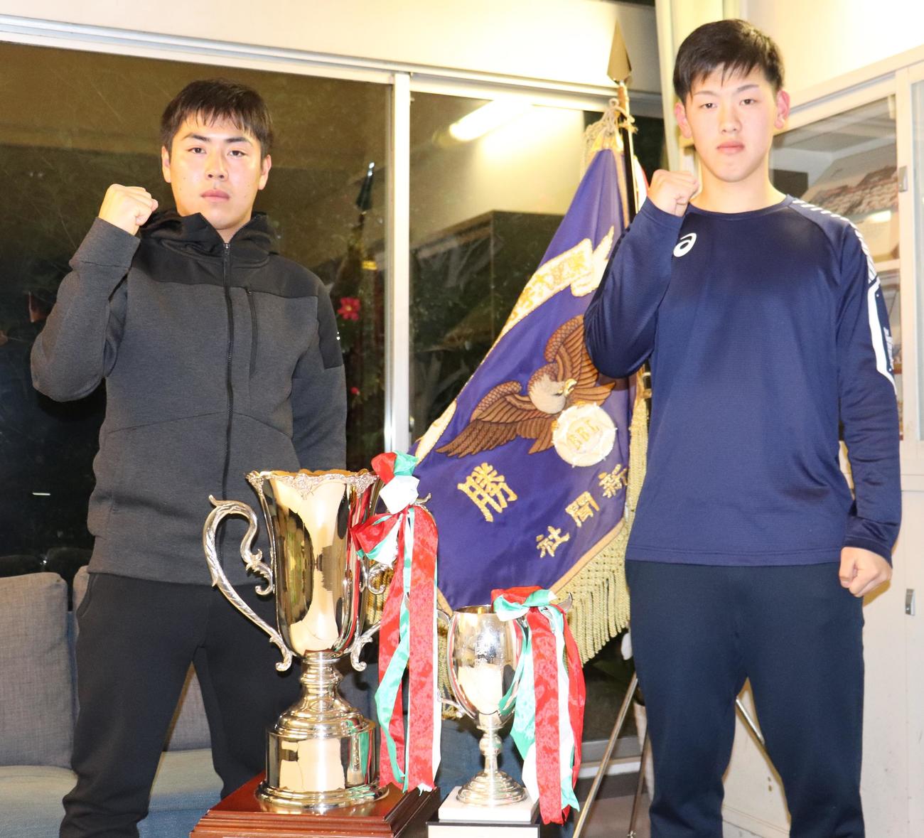 昨秋東都大学野球リーグを制した時の優勝旗と優勝カップを前に、大学での活躍を誓う根本（左）と岩本