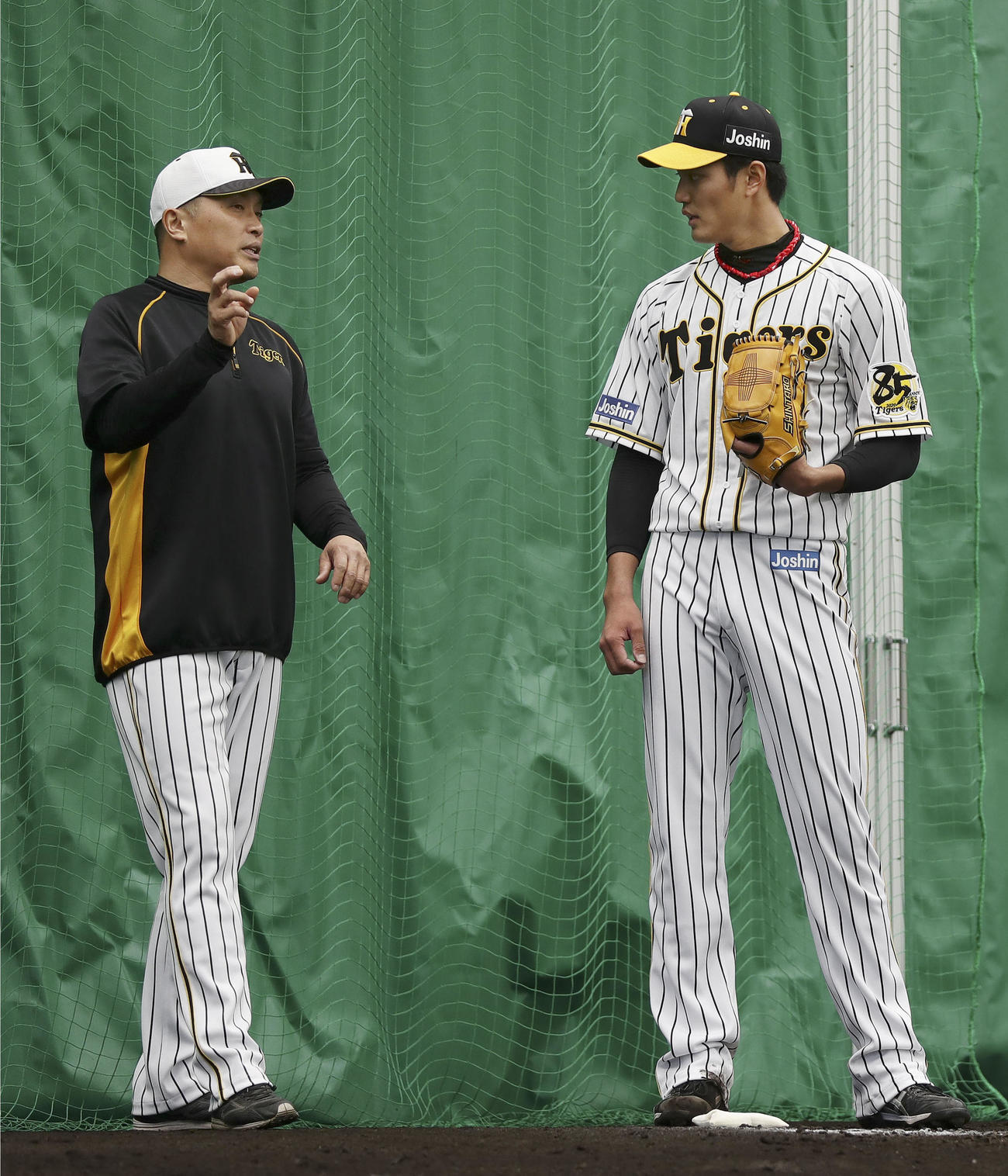 ブルペンで、山本昌臨時コーチ（左）から指導を受ける阪神・藤浪（共同）