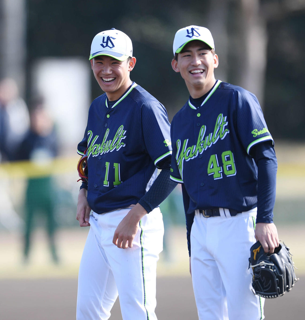 投内連係の合間に笑顔を見せるヤクルト奥川。右は金久保（撮影・鈴木みどり）