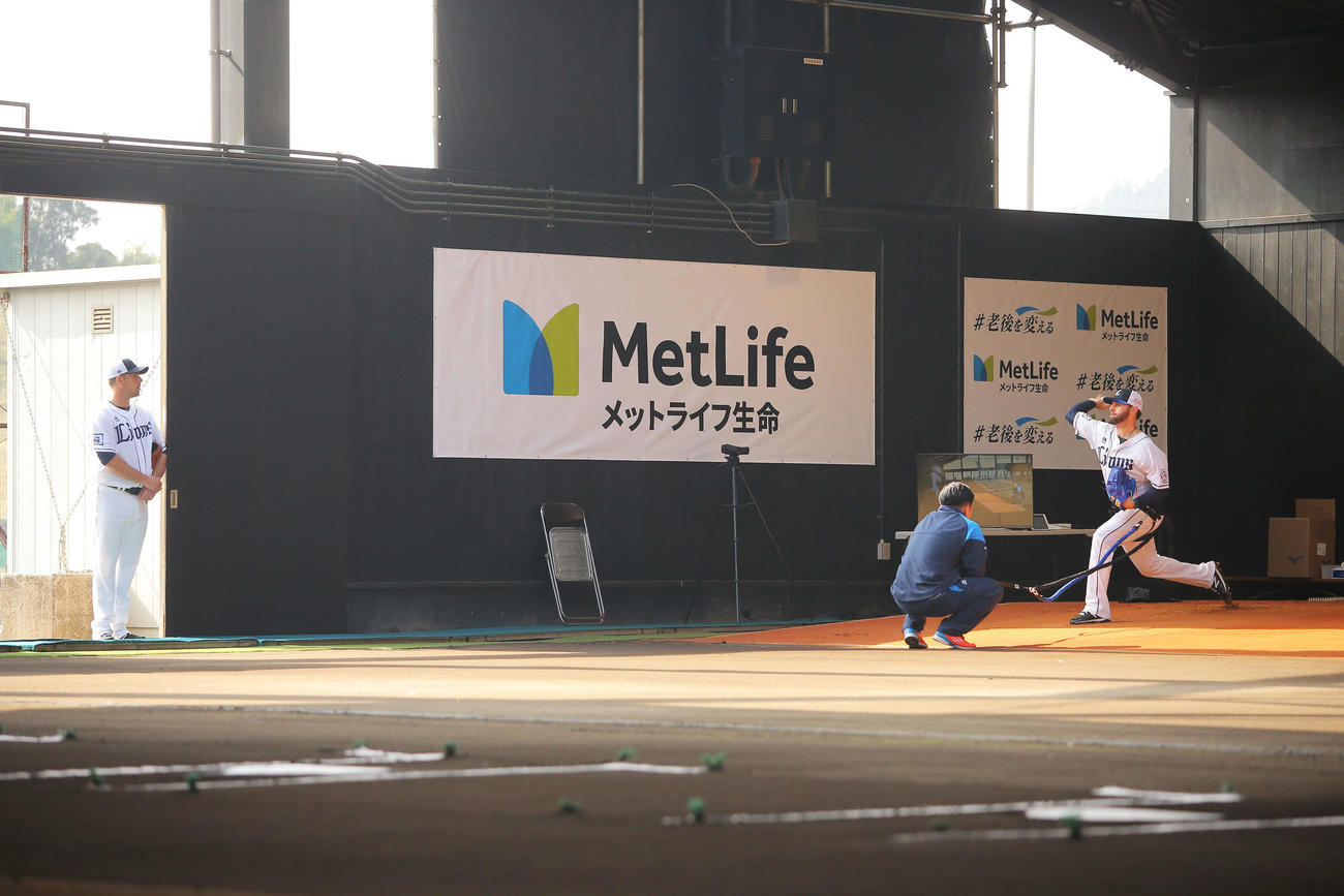 西武ニール（右）のブルペン投球を静かに見つめるノリン（撮影・河田真司）
