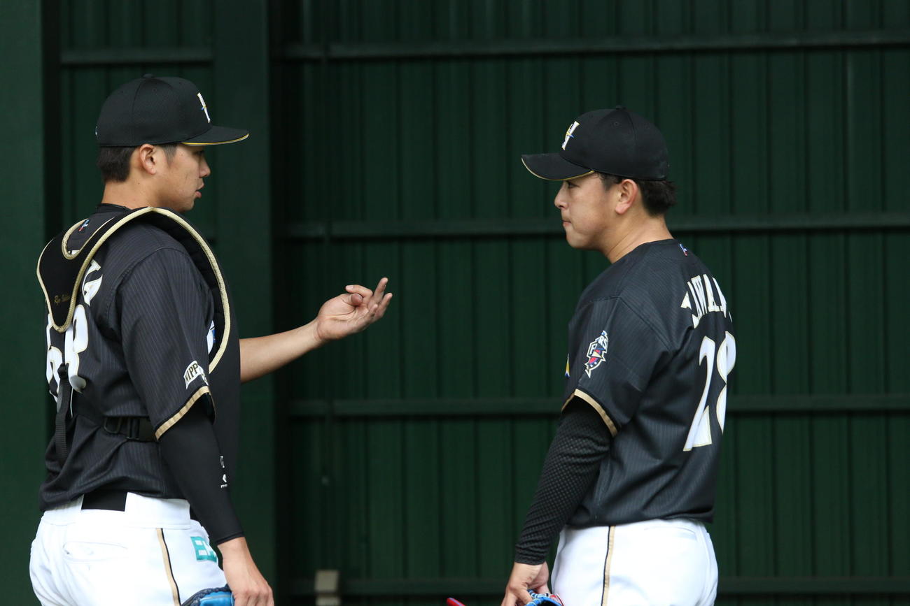 ブルペン後、球を受けた石川亮（左）と話す日本ハム河野（撮影・田中彩友美）