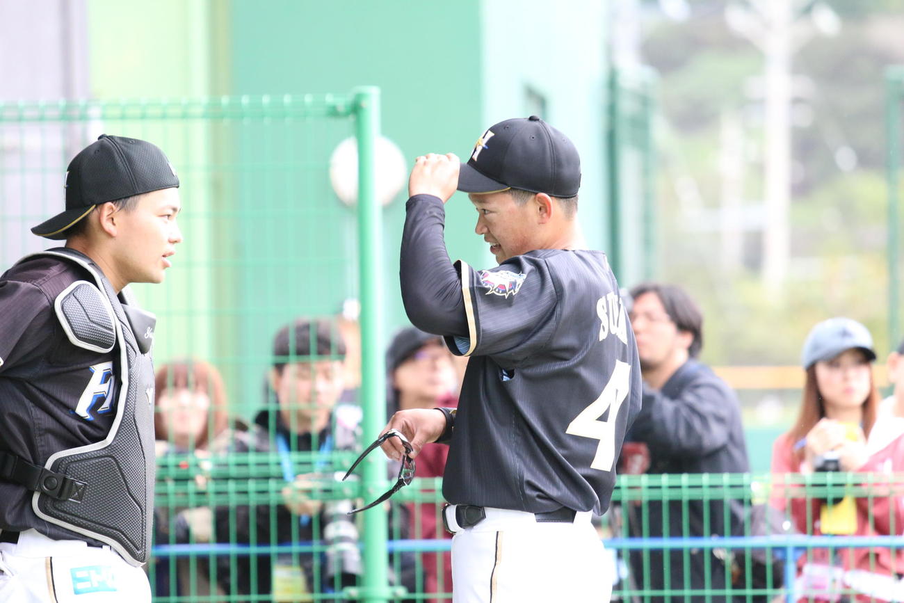 ブルペン後、球を受けた田宮（左）と話す日本ハム鈴木健（撮影・田中彩友美）