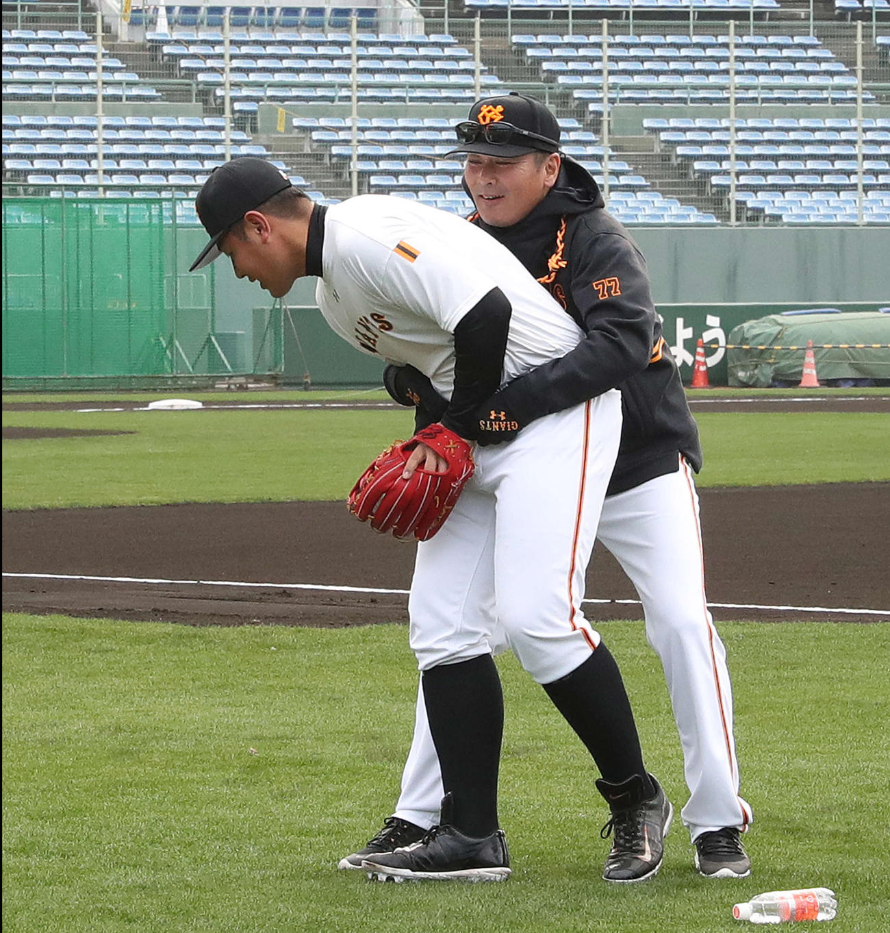 早出練習で巨人元木コーチ（右）とじゃれ合う岡本（撮影・河野匠）