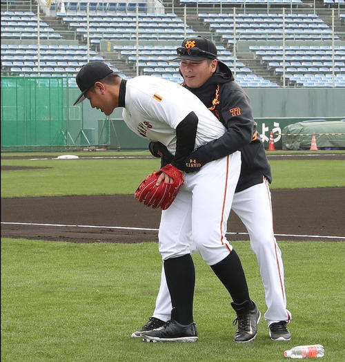 早出練習で巨人元木コーチ(右)とじゃれ合う岡本(撮影・河野匠)