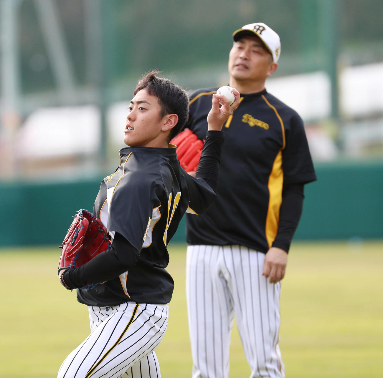 山本昌臨時投手コーチ（奥）の指導を受けチェンジアップを試投する小川一平（撮影・清水貴仁）