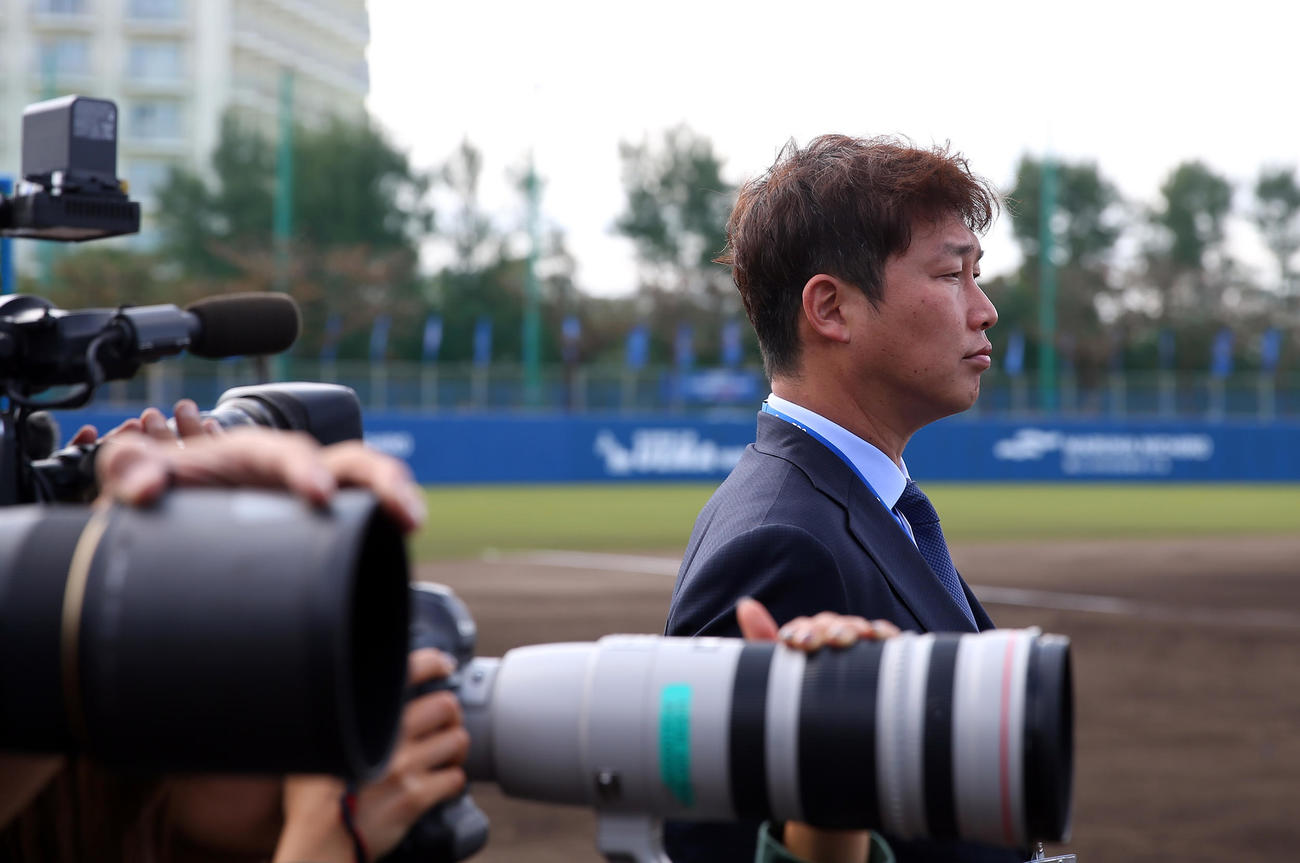 テレビの取材でDeNAキャンプに訪れた新井貴浩氏は真剣な表情で練習を見つめた（撮影・大野祥一）
