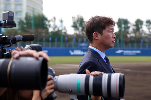テレビの取材でDeNAキャンプに訪れた新井貴浩氏は真剣な表情で練習を見つめた（撮影・大野祥一）
