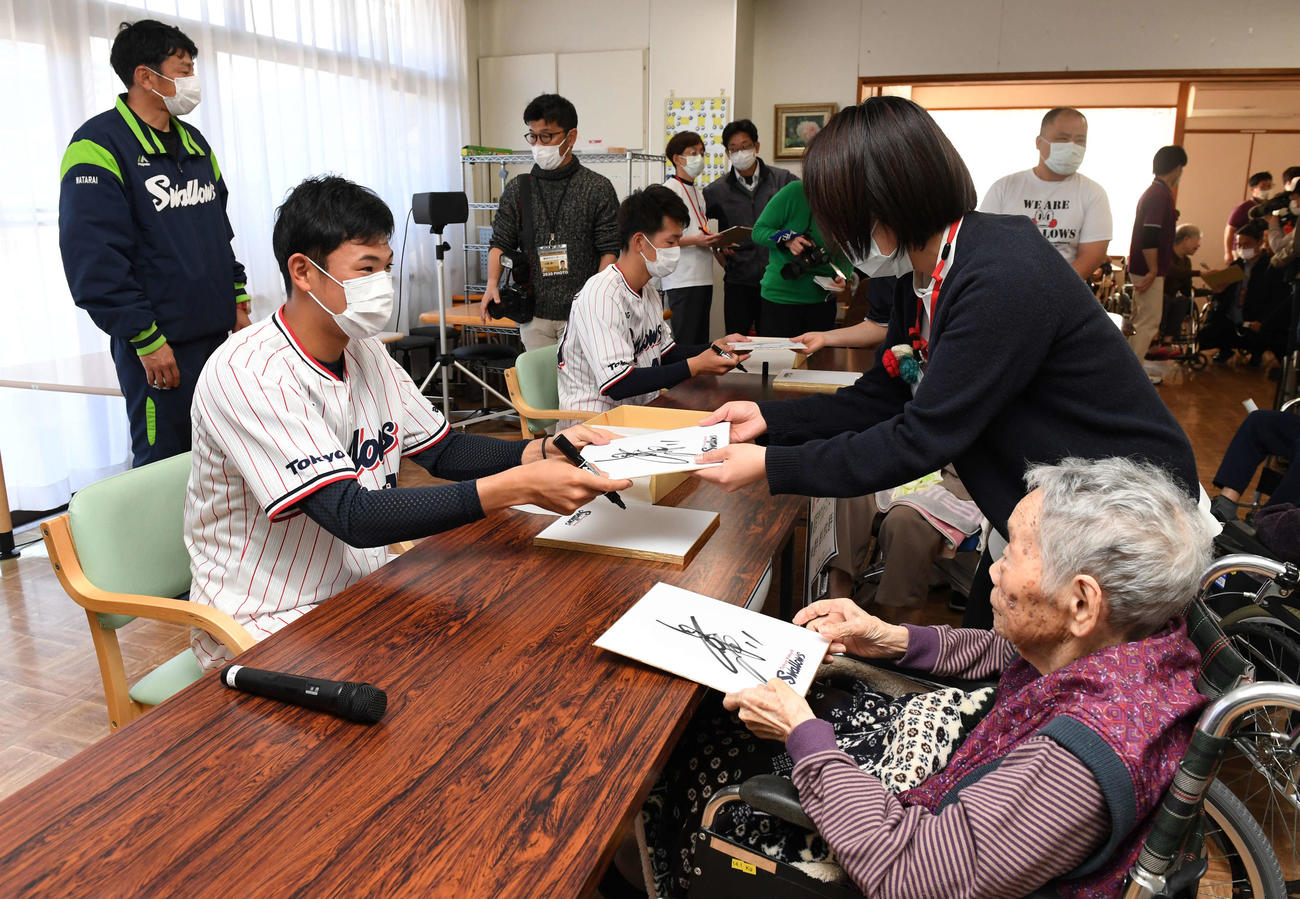 介護老人保健施設「並木の里」を慰問し、入居者にサインを手渡すヤクルト奥川（左手前）と市川（撮影・鈴木みどり）