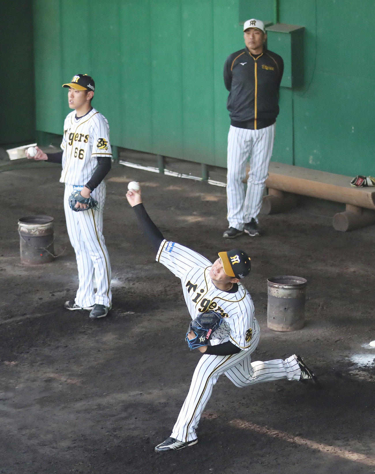 はじめてブルペンに入り投球練習を行う阪神西純矢（手前）、奥は山本昌臨時投手コーチ（撮影・清水貴仁）