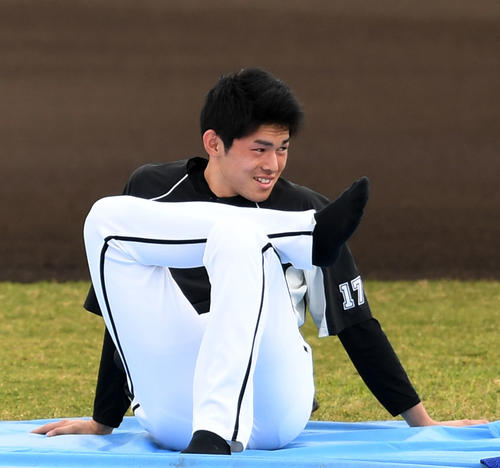 ストレッチしながら笑顔を見せるロッテ佐々木朗（撮影・横山健太）