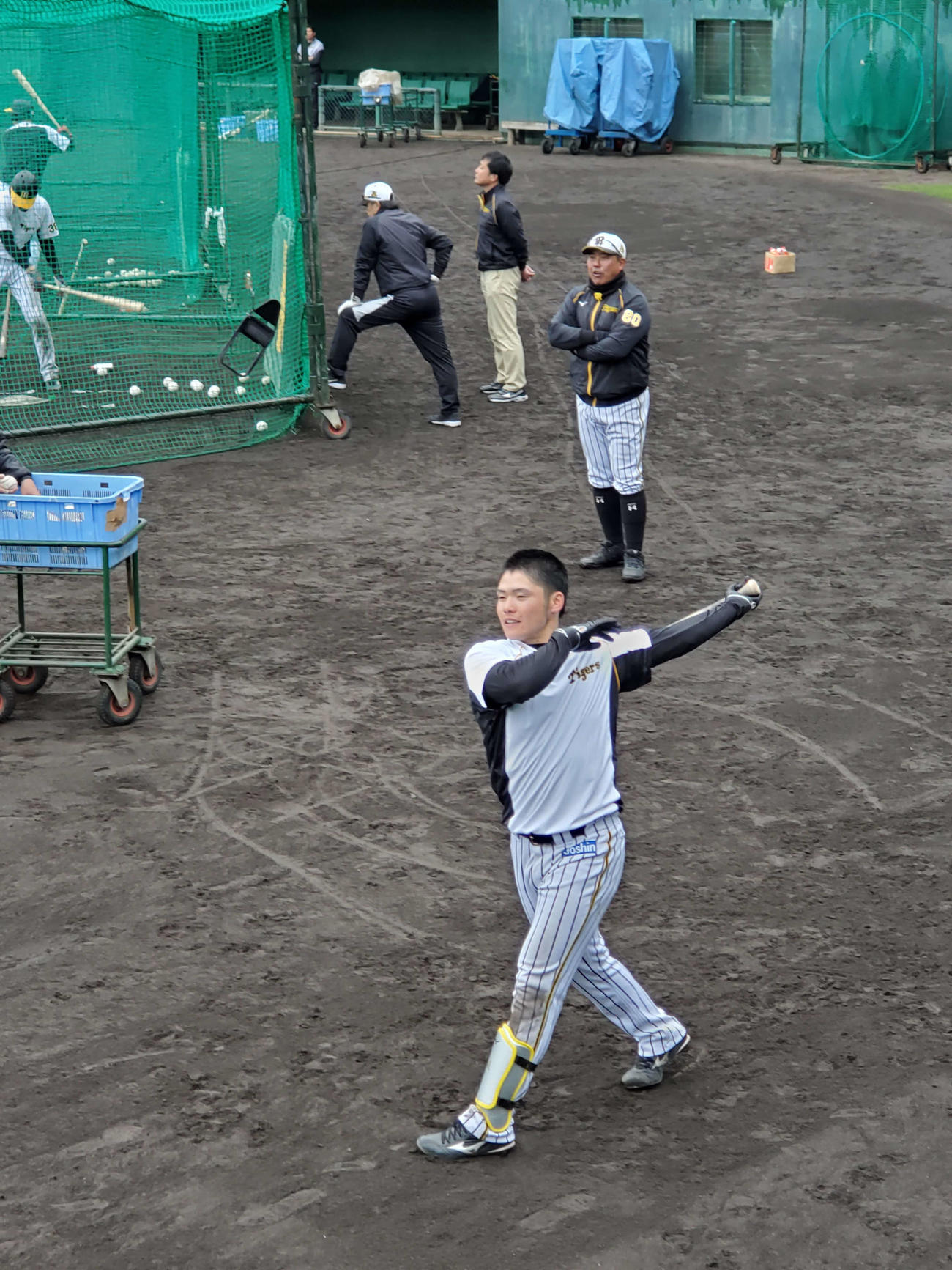 阪神小野寺は居残り特打のロングティー打撃で躍動感たっぷりの振りを披露。後方は北川コーチ（撮影・酒井俊作）