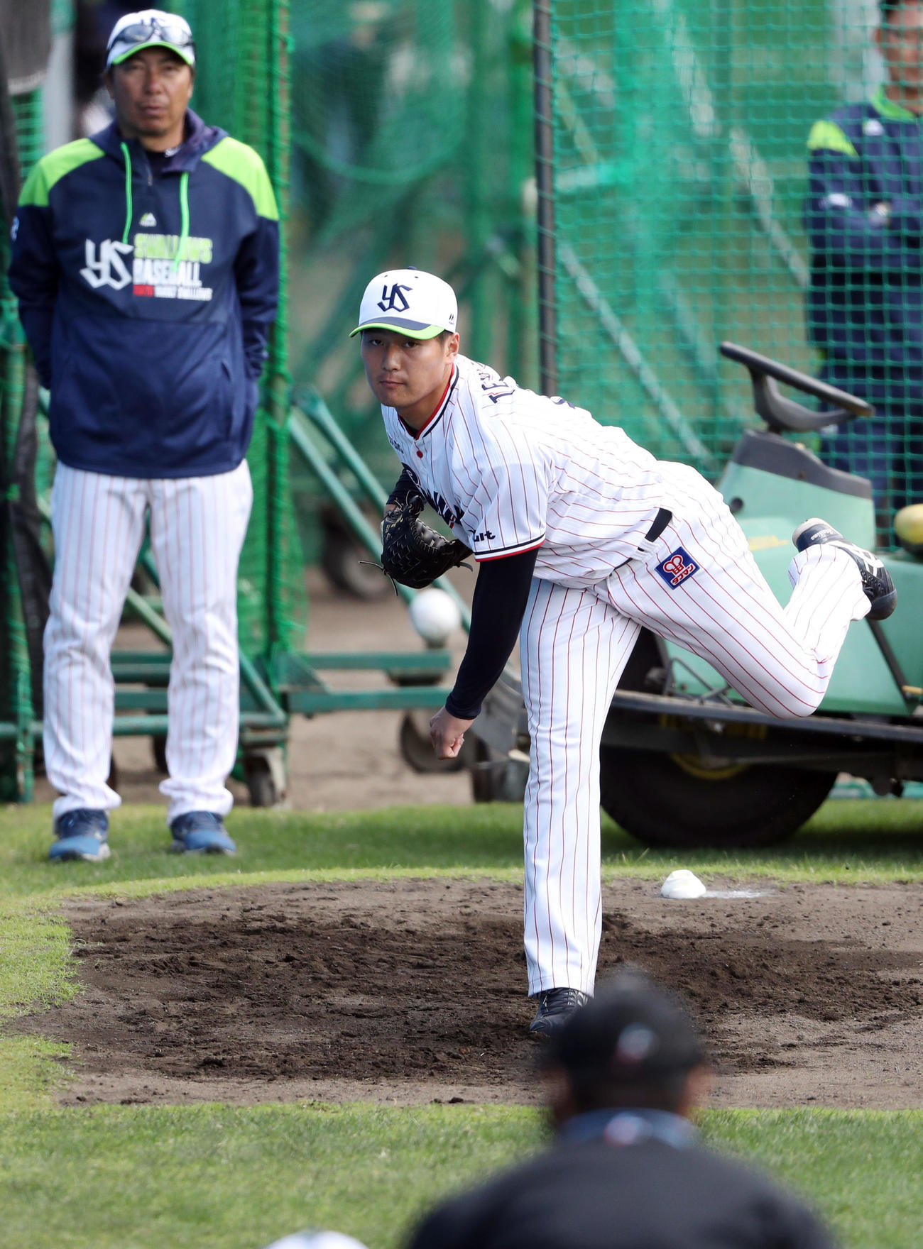 シート打撃の登板前、高津監督（後方）が見守る中、ブルペンで投げ込む寺島（撮影・狩俣裕三）