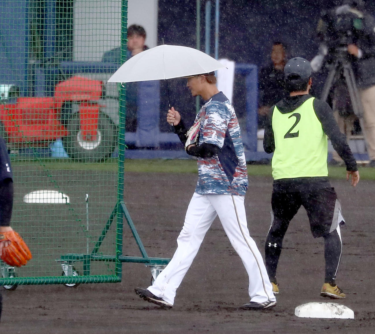 練習中、突然の雨で傘をさしてベンチに戻る西川（撮影・黒川智章）