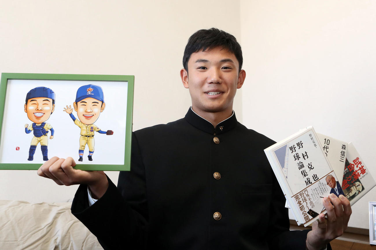 1月5日、入寮し、星稜の山下名誉監督が持たせてくれた野村氏らの本と、山瀬とのバッテリーの似顔絵を手に笑顔を見せる奥川