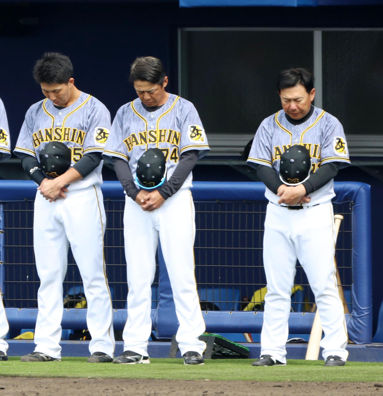 日本ハム対阪神　野村克也氏の訃報を受け練習試合開始前に黙とうする藤本コーチ（中央、久慈コーチ（右）ら、左は片山（撮影・加藤哉）