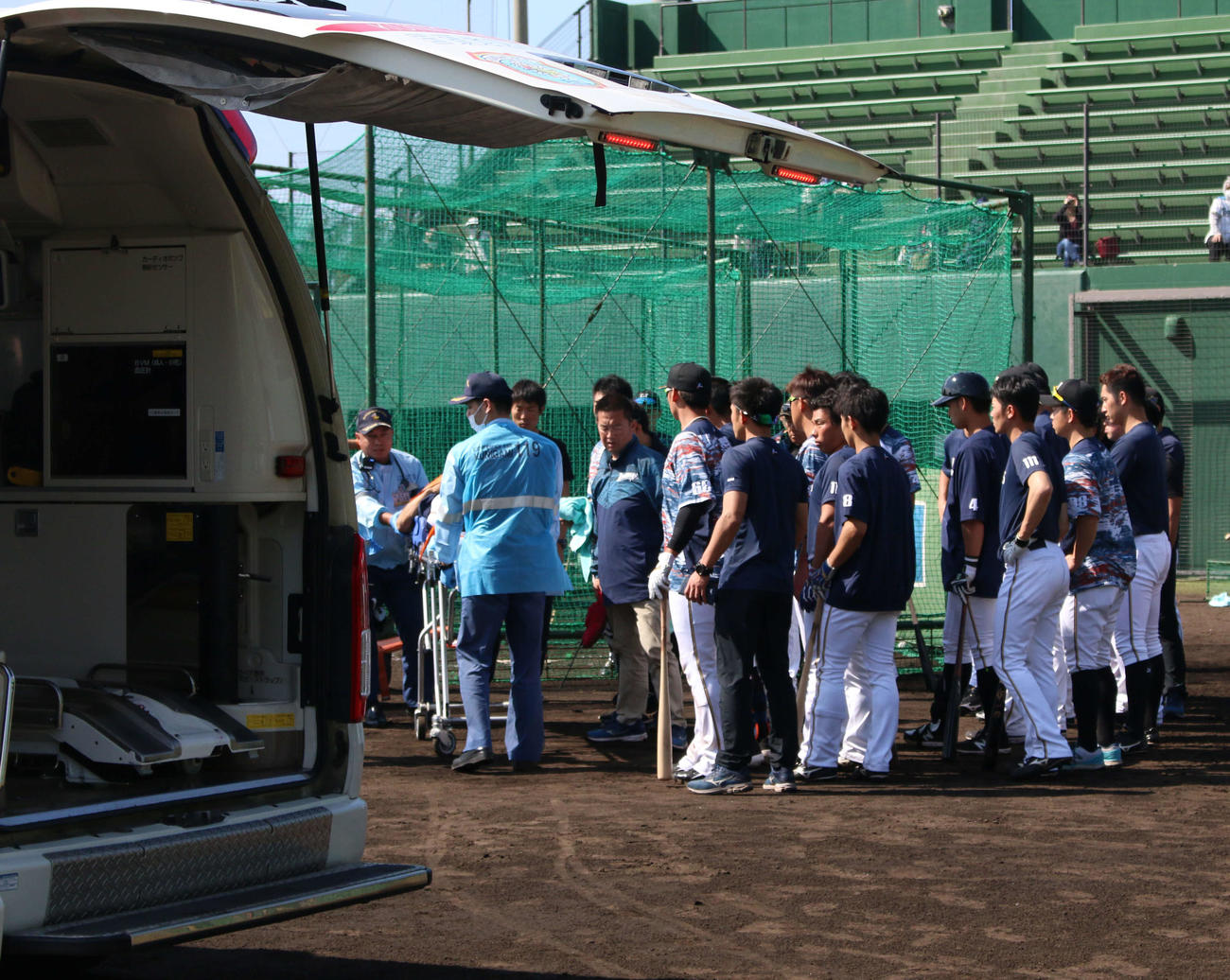 2軍の沖縄・国頭キャンプの練習中に倒れた城石2軍内野守備コーチが選手らに囲まれながら救急車へ＝午後1時33分頃（撮影・木下大輔）