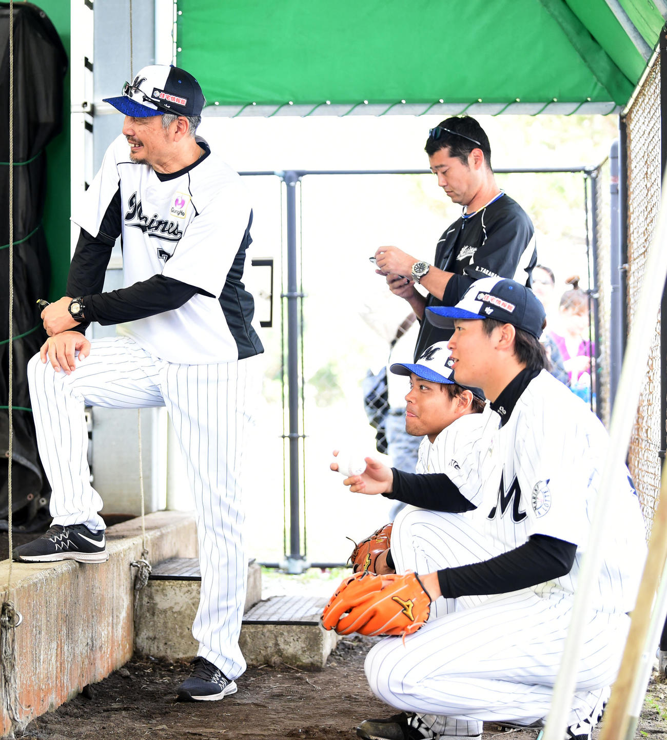 ロッテ佐々木朗の投球を笑顔で見つめるロッテ吉井コーチ（左）。同2人目から見学する佐々木千と二木（撮影・横山健太）