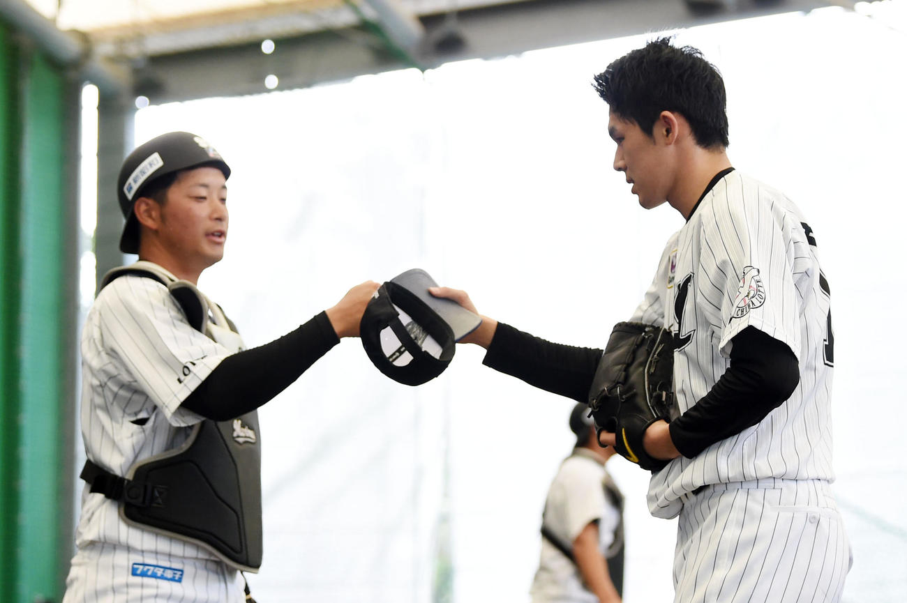 ブルペンでの投球を終え、捕手とグータッチするロッテ佐々木朗（右）（撮影・横山健太）