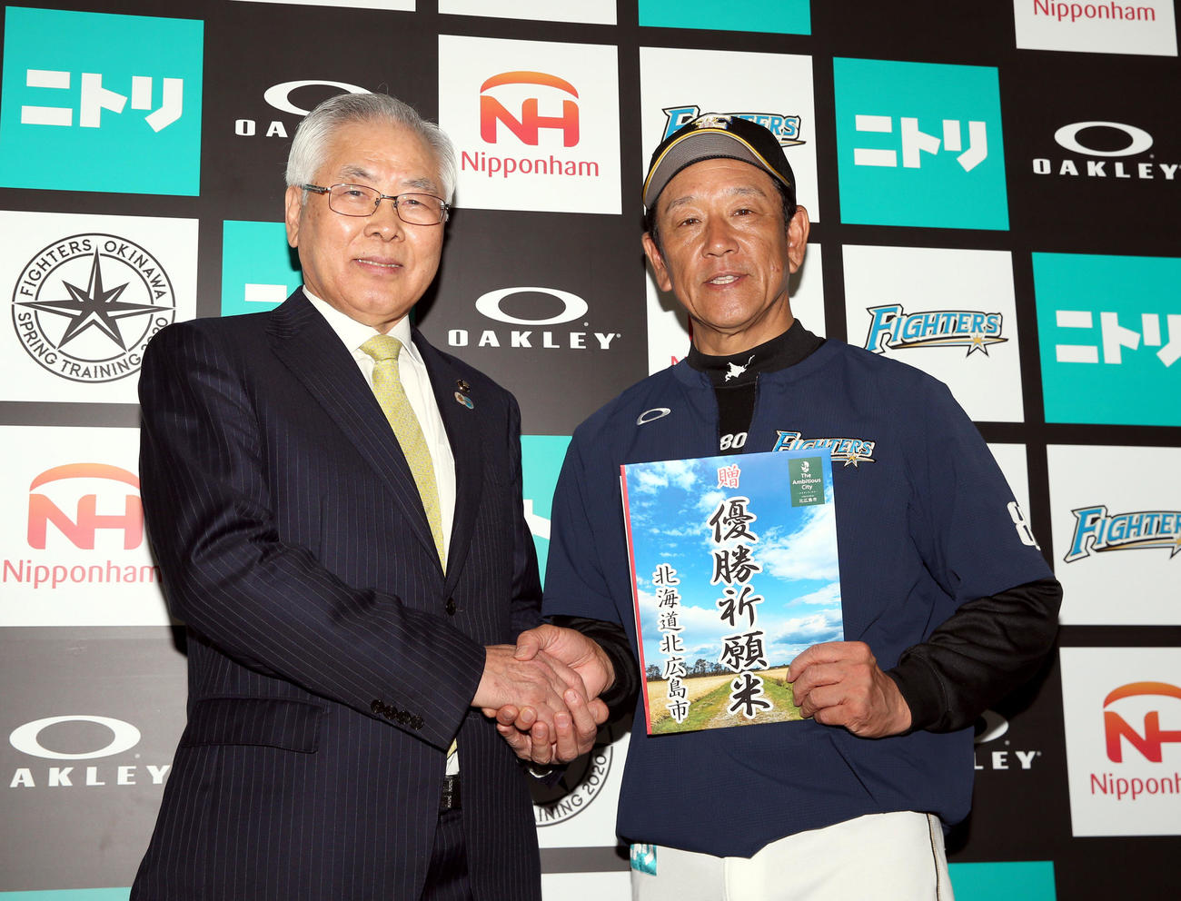 試合前、激励に訪れた北広島市の上野市長（左）と握手する日本ハム栗山監督（撮影・佐藤翔太）