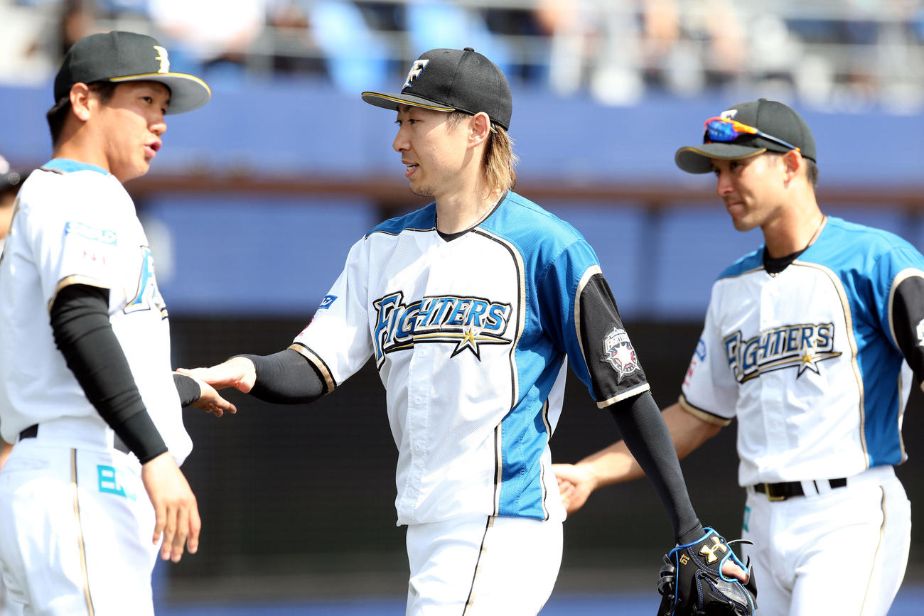 日本ハム対楽天　ナインとタッチを交わしながらベンチに戻る日本ハム金子（中央）（撮影・佐藤翔太）