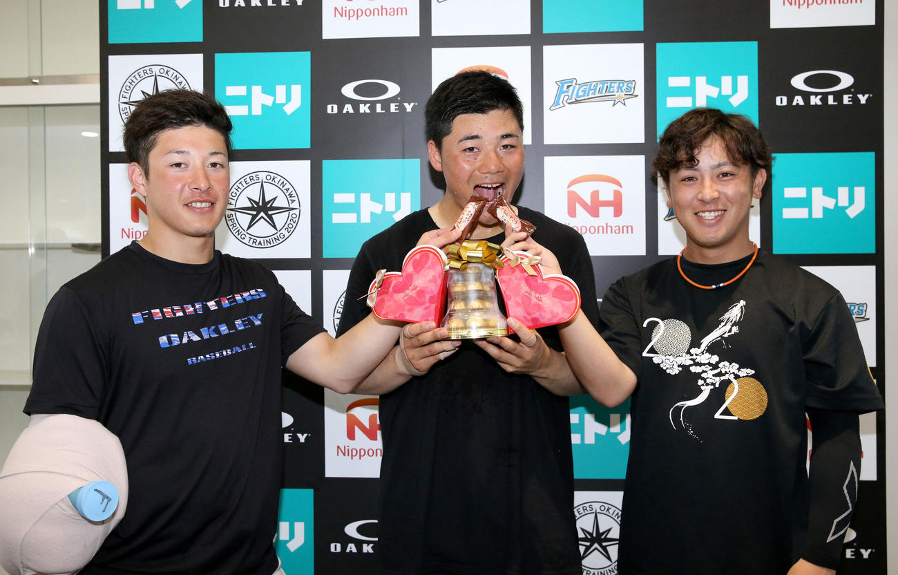 報道陣からプレゼントされたチョコレートを日本ハム吉田輝（左）と河野（右）から食べさせてもらう清宮（撮影・佐藤翔太）