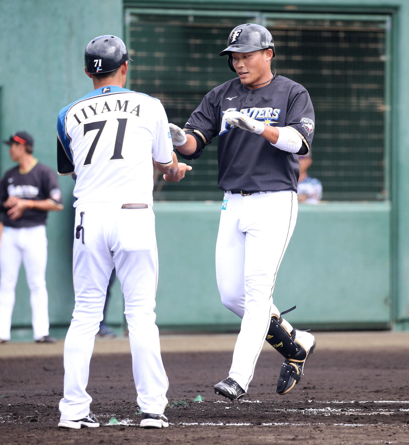 紅組対白組　2回表紅組1死、先制となる右越え本塁打を放ち日本ハム飯山コーチ（左）とタッチを交わす王柏融（撮影・佐藤翔太）