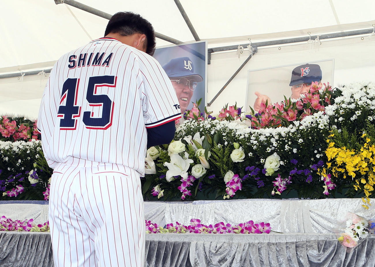 キャンプ地に設置された故野村克也さんの献花台で手を合わせる嶋（撮影・狩俣裕三）