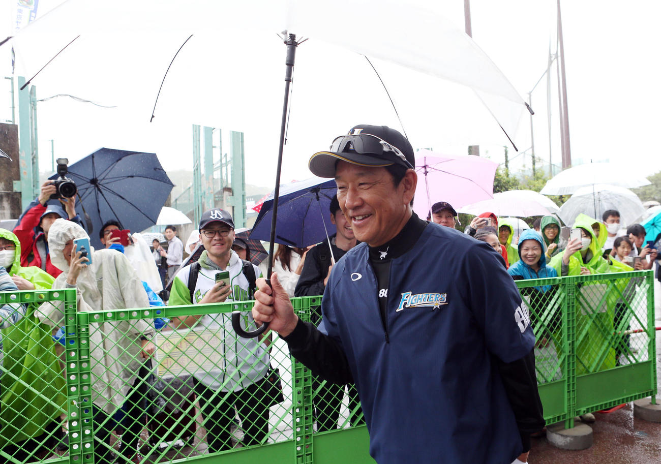 傘を差しながら、笑顔で移動する栗山監督（撮影・狩俣裕三）