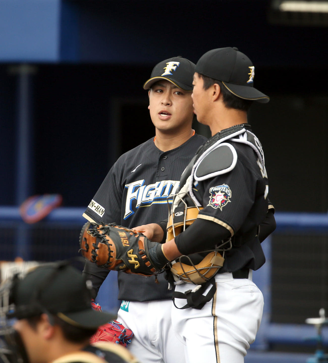 投内連係中、会話する日本ハム河野（中央奥）と鶴岡（撮影・佐藤翔太）