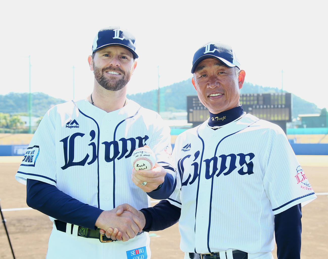 西武の開幕投手に決まったニール（左）は辻監督と笑顔で握手を交わす（撮影・足立雅史）