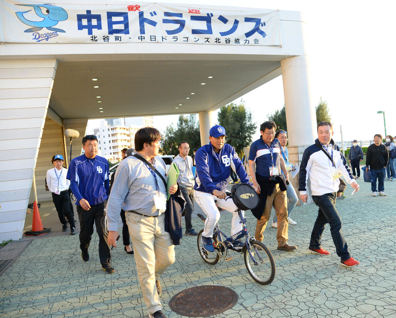 キャンプ地の北谷に戻り、約1時間の練習を行い記者に囲まれ自転車で引き揚げる与田監督（撮影・森本幸一）