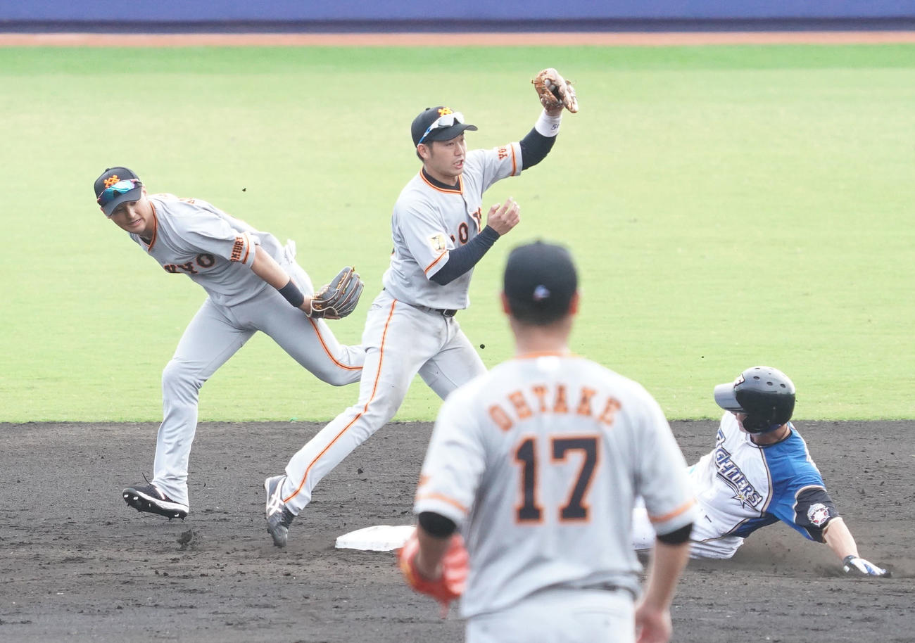 8回表日本ハム1死一塁、近藤のゴロを好捕した二塁手吉川尚（左）は、遊撃手山本にグラブトスして走者松本を封殺。手前は巨人5番手の大竹（撮影・加藤諒）