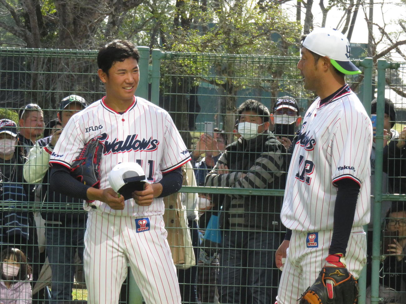 ブルペンで2度目の投球練習を終え、小山田ブルペン捕手と話すヤクルトのドラフト1位、奥川（左）