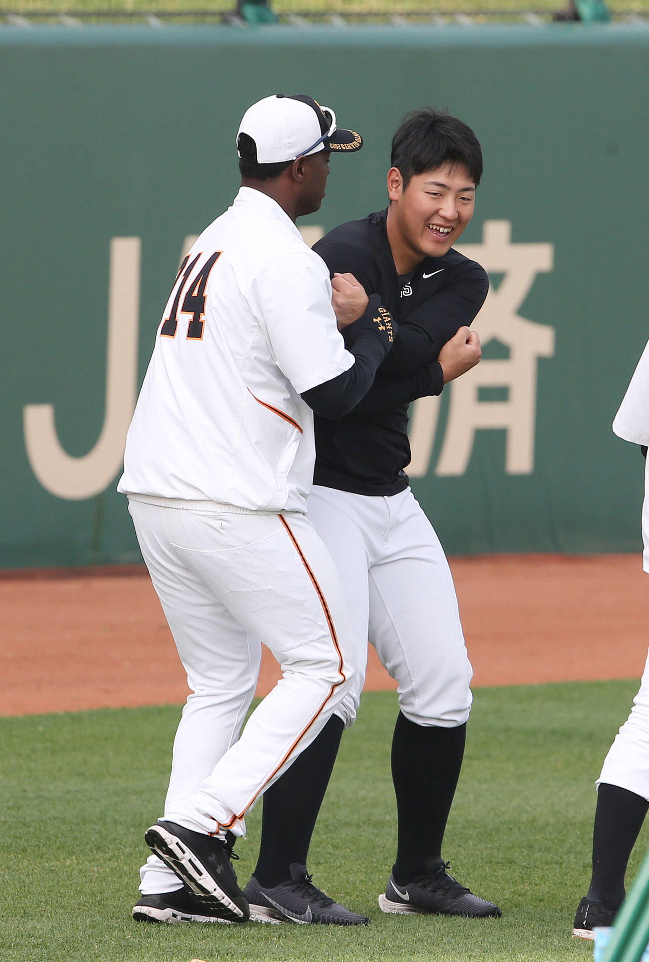 練習前、巨人モタ（左）とじゃれ合う岡本（撮影・河野匠）