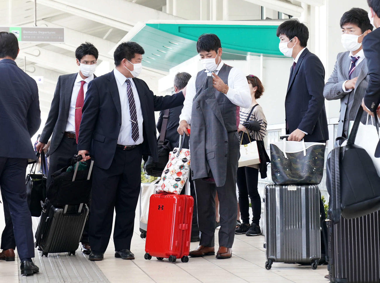 巨人沖縄キャンプを終え、那覇空港で通りがかりの人に声をかけられる岡本（中央）。空港では乗客のみならず、職員も含むほとんどの人がマスクを着用していた（撮影・加藤諒）