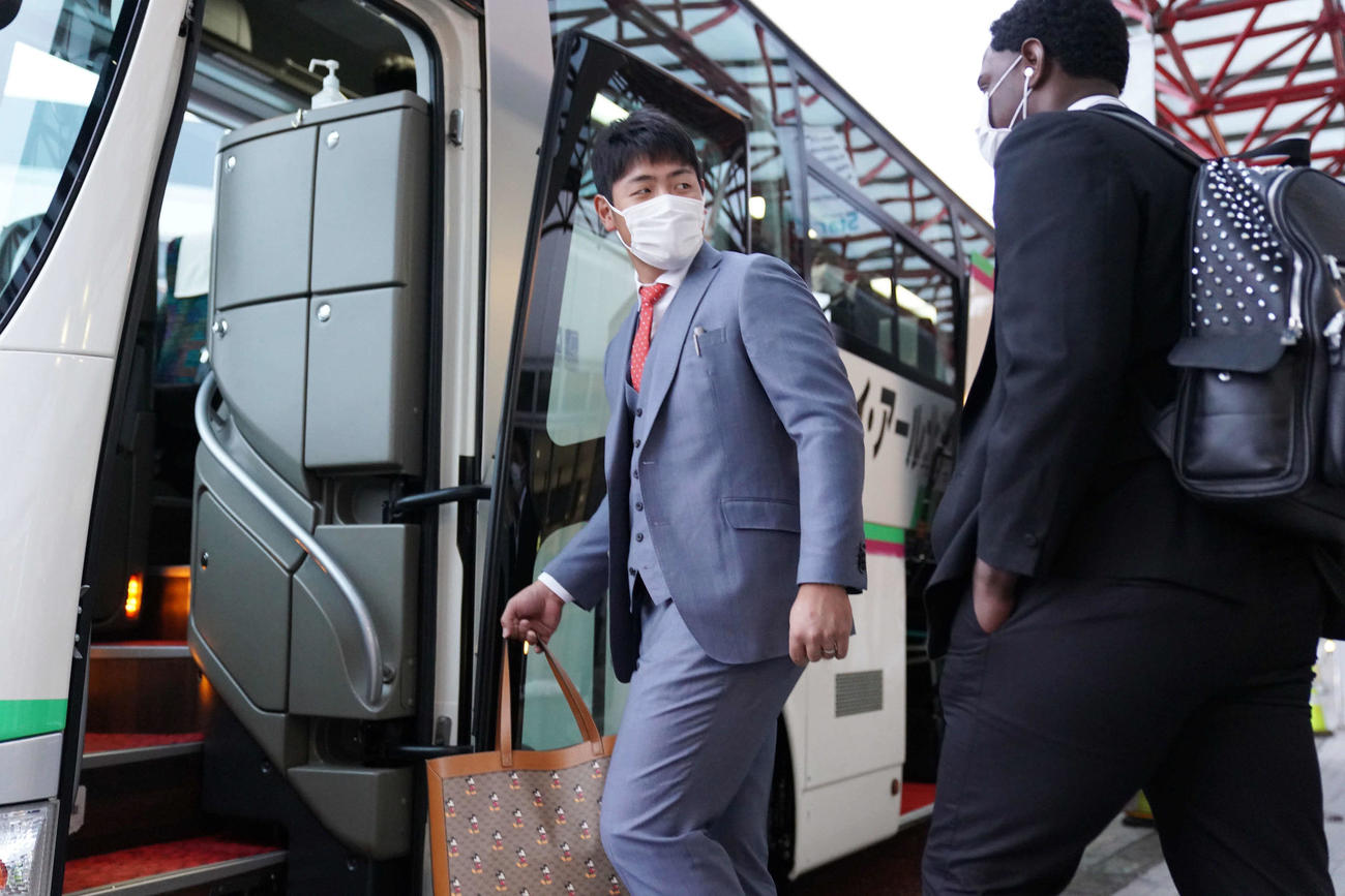 日本ハムとのオープン戦のため、新千歳空港に到着し、バスに乗り込む順番を譲りあう巨人岡本（中央）とモタ（撮影・加藤諒）