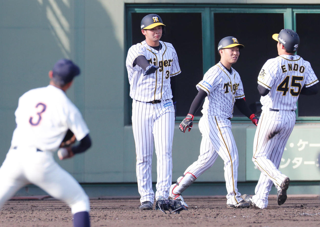 阪神対大商大　9裏阪神1死二、三塁、小野寺の2点適時打で生還した井上（左）と遠藤（右）。中央は次打者の藤田（撮影・清水貴仁）