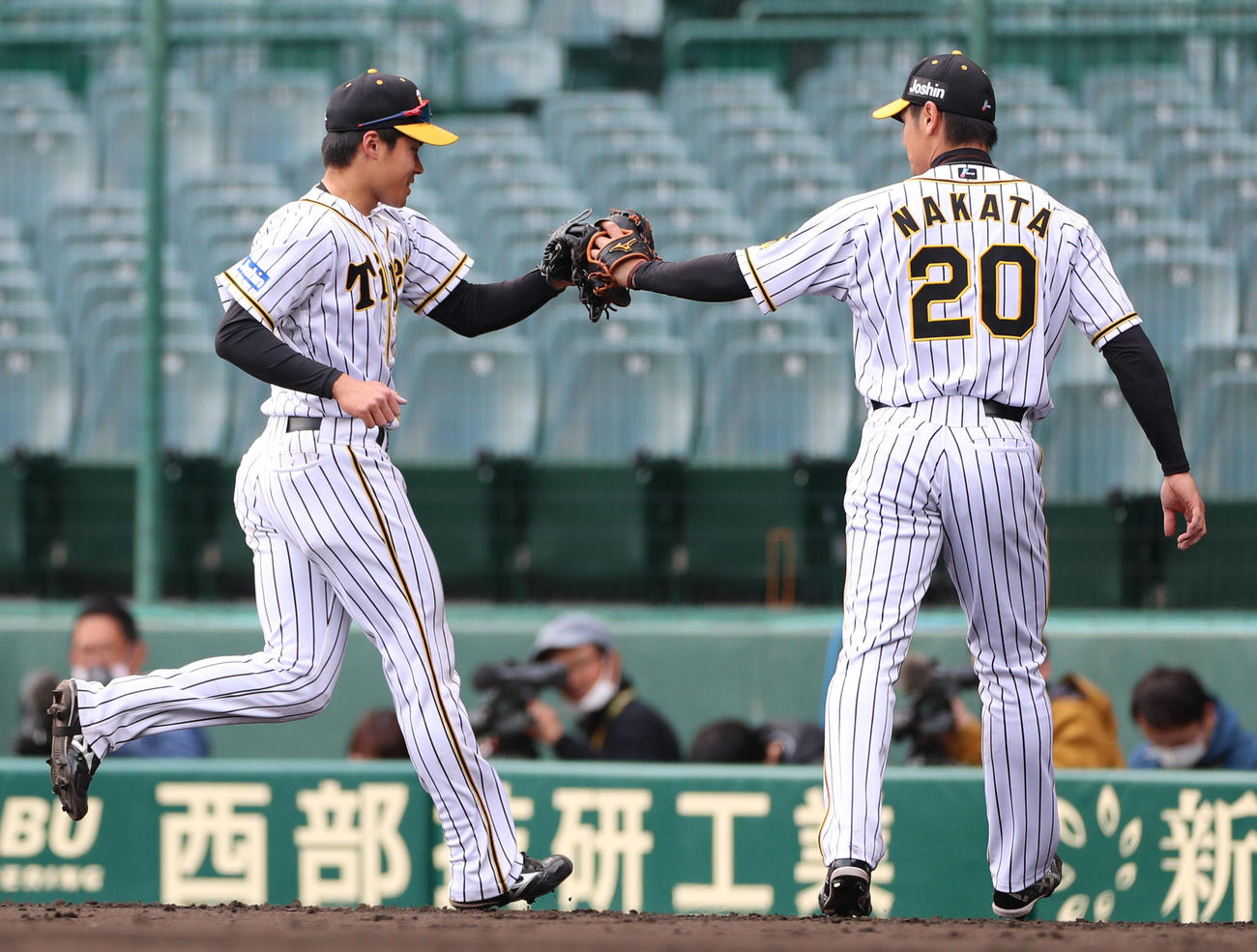 7回の守備を終えベンチ前で中田賢一（右）とタッチを交わす遠藤成（撮影・清水貴仁）
