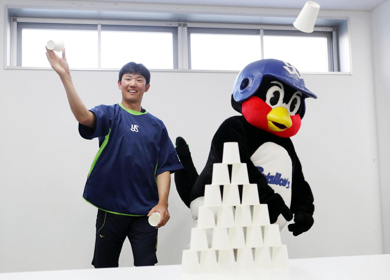 遊びながらできる練習法で、つば九郎といっしょに紙コップを投げる奥川（撮影・狩俣裕三）