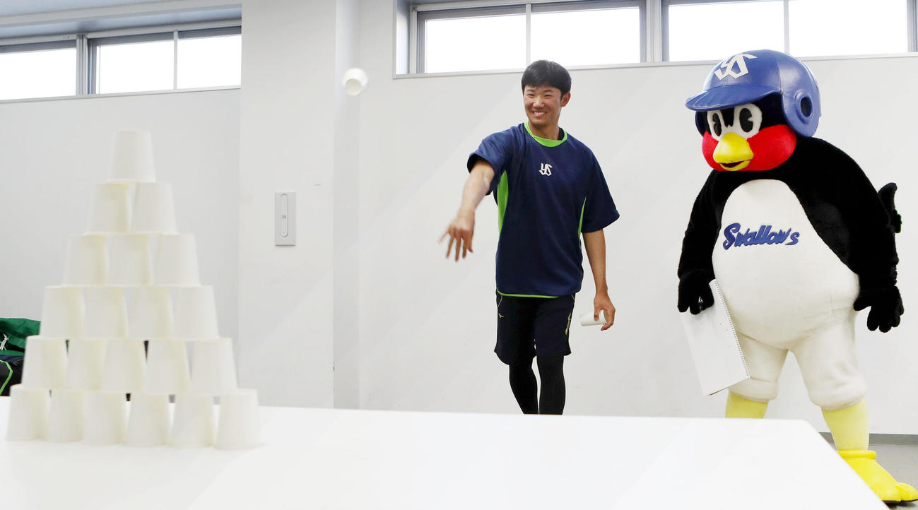 遊びながらできる練習法で、つば九郎の前で紙コップを投げる奥川（撮影・狩俣裕三）